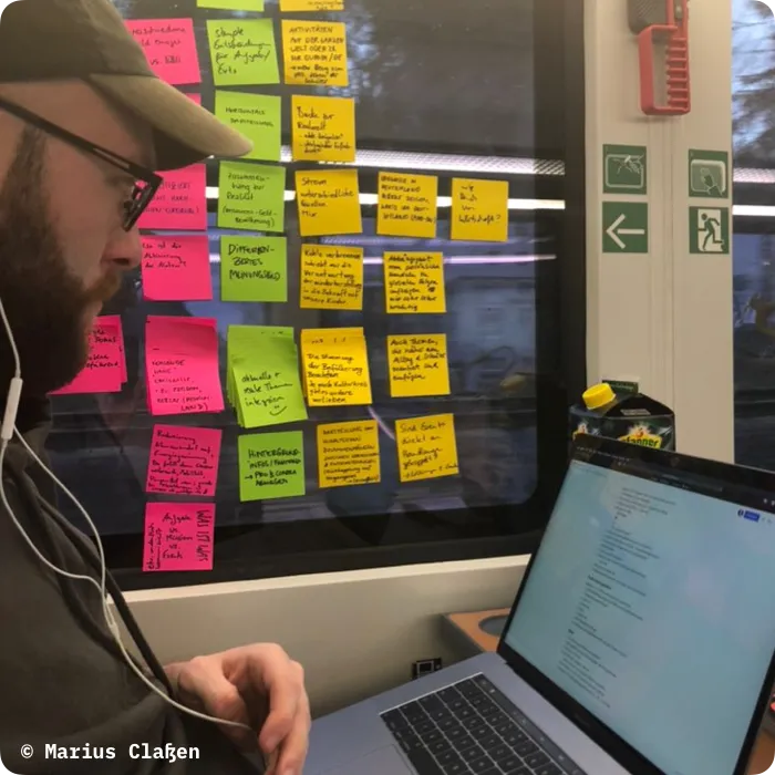 A guy sitting on a train with the entire window next to him filled with post-its